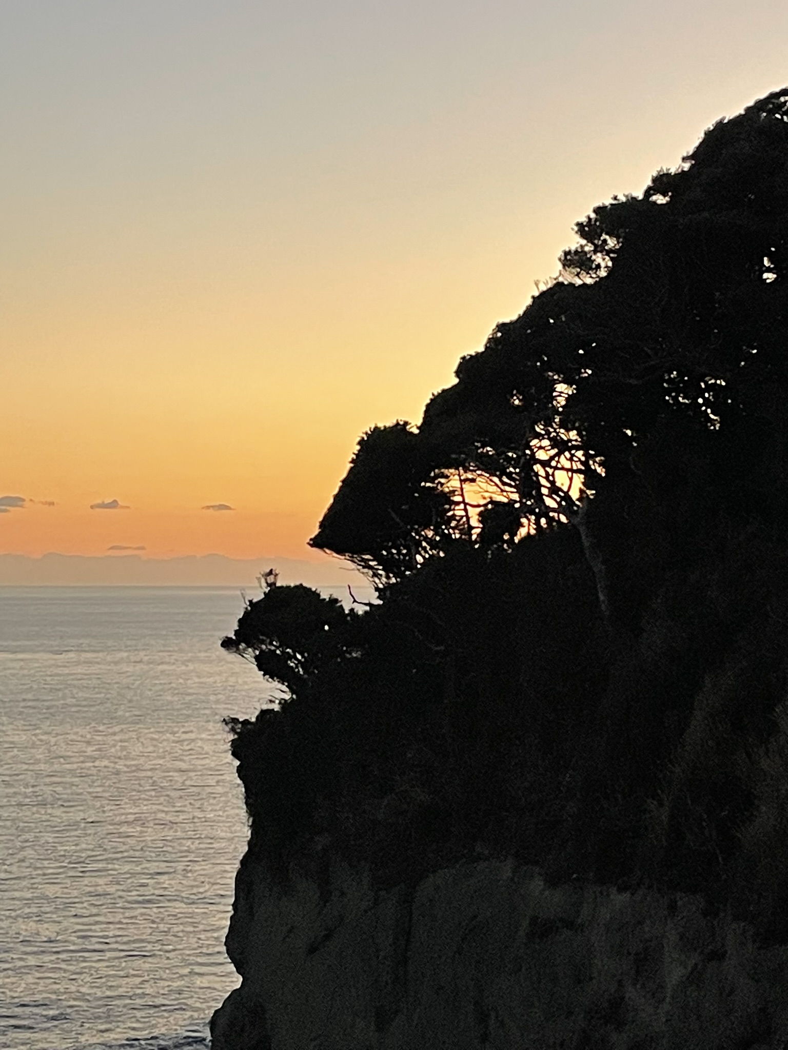 A cliff contrasted against the sunset sky
